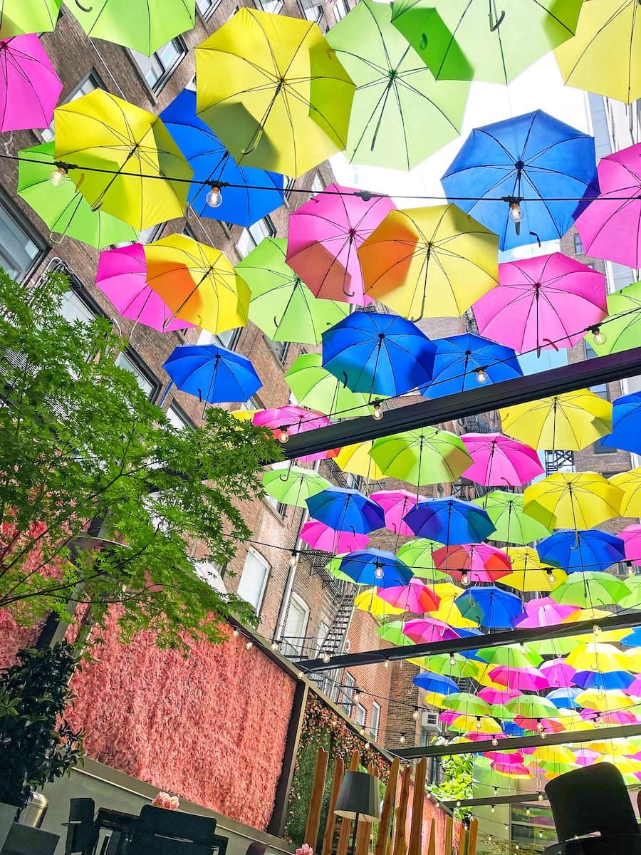 Colorful umbrellas suspended in the air above a street, with buildings in the background.