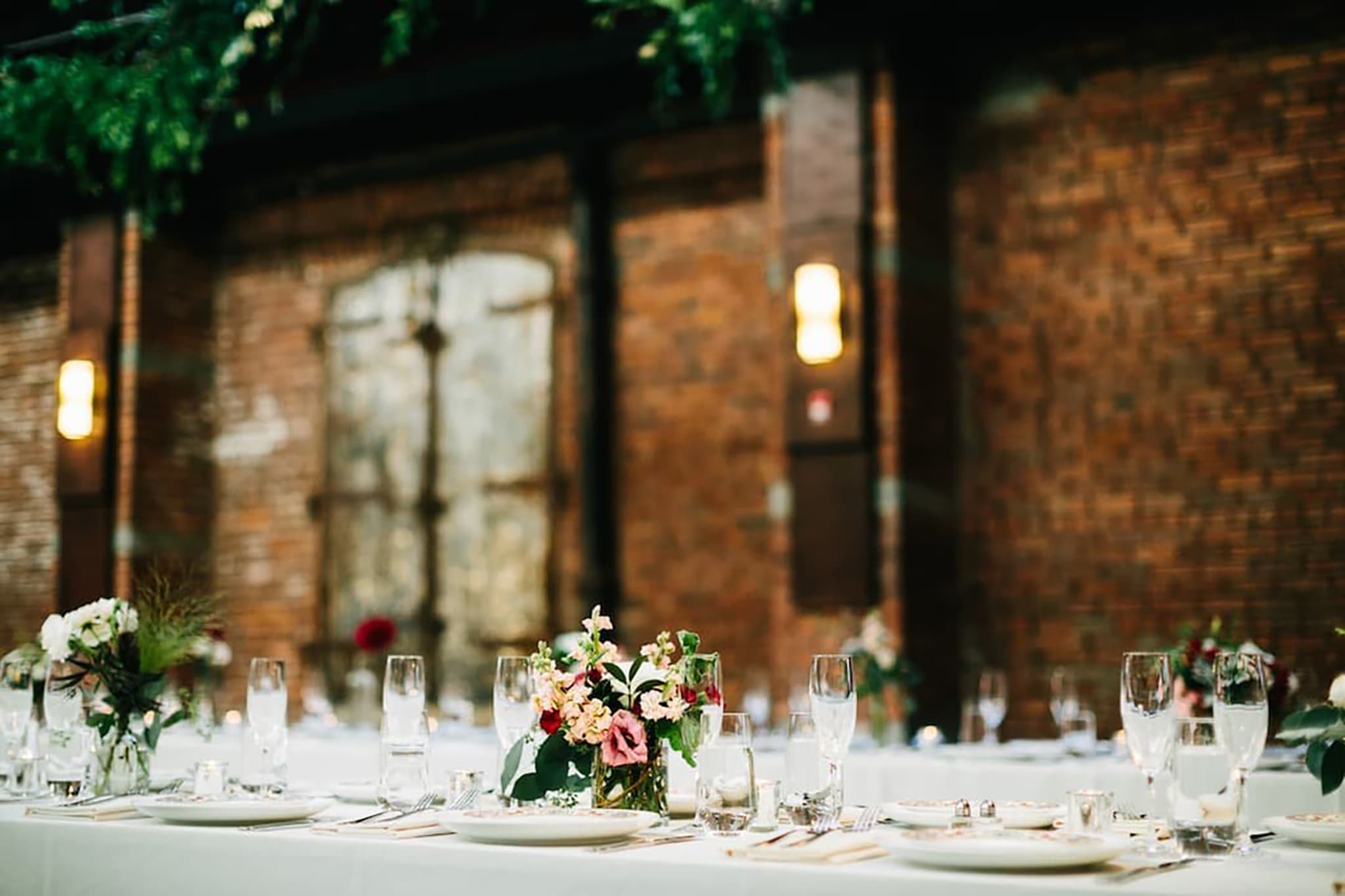 Close-up of wedding table with glassware, white linens, and a lush floral centerpiece.
